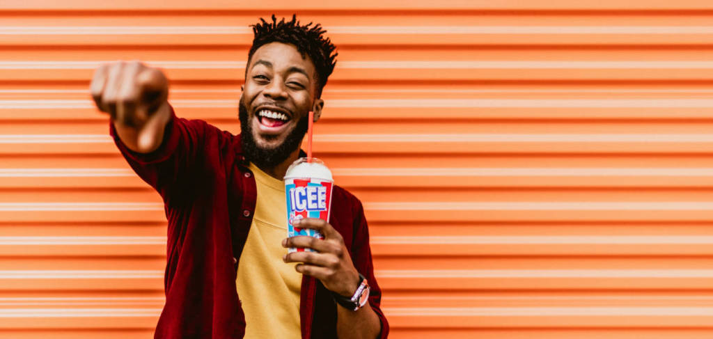A man smiling drinking an ICEE